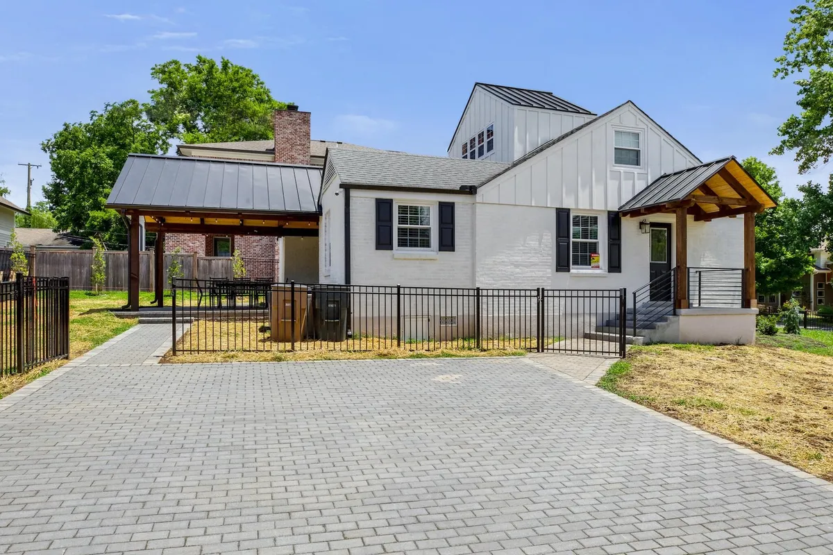 This image shows the front facade of the house with a welcoming porch, paved driveway, and an inviting outdoor seating area. The lush yard is perfect for family gatherings, children’s play, or relaxing afternoons under the sun.